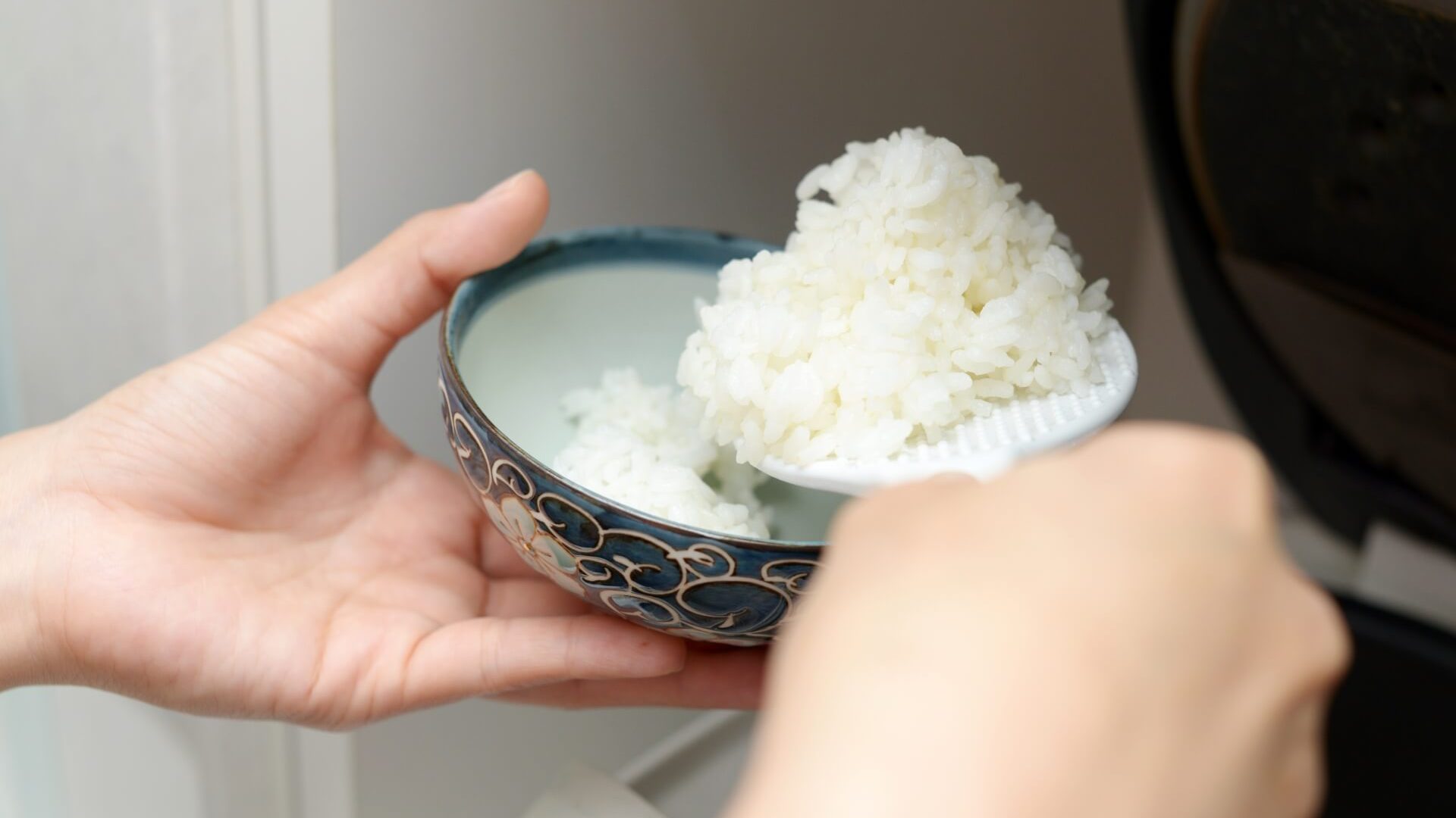 炊飯器で炊きあがったお米を茶碗に入れている画像
